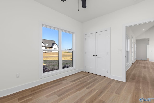 unfurnished bedroom featuring baseboards, a ceiling fan, light wood finished floors, and a closet