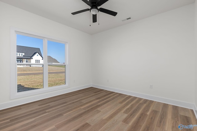 spare room featuring baseboards, ceiling fan, wood finished floors, and visible vents