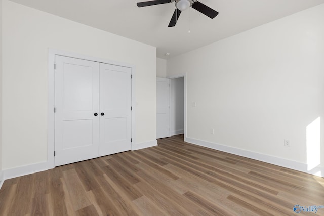 unfurnished bedroom with baseboards, a ceiling fan, wood finished floors, and a closet