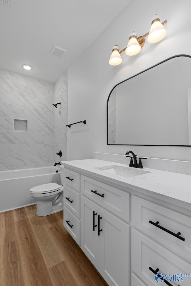 bathroom with shower / tub combination, vanity, toilet, wood finished floors, and visible vents