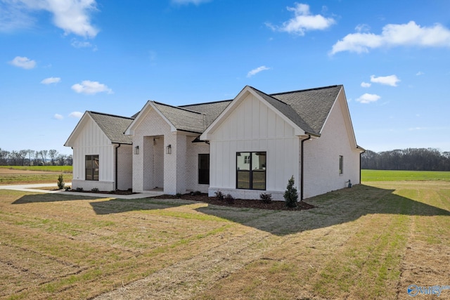 modern farmhouse featuring board and batten siding, brick siding, roof with shingles, and a front lawn