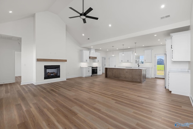 unfurnished living room with wood finished floors, a fireplace, high vaulted ceiling, recessed lighting, and a ceiling fan