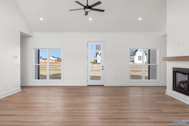 unfurnished living room featuring a healthy amount of sunlight, a fireplace, a ceiling fan, and wood finished floors