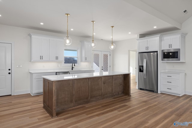 kitchen featuring light countertops, a sink, light wood-style floors, and stainless steel appliances