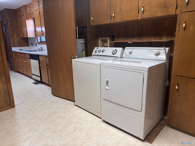 laundry area featuring electric water heater, cabinets, independent washer and dryer, and sink