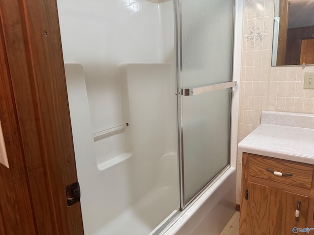 bathroom with tasteful backsplash, vanity, enclosed tub / shower combo, and tile walls