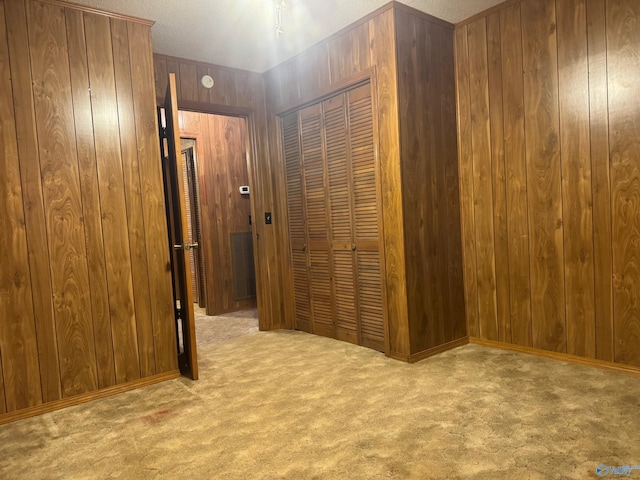 hall with light carpet, wooden walls, and a textured ceiling