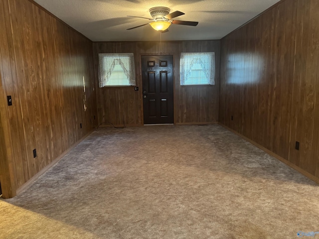 entryway featuring plenty of natural light, ceiling fan, and wooden walls