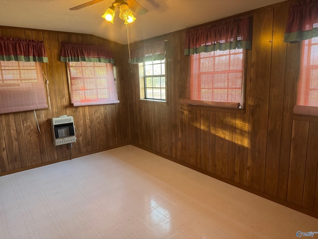 empty room with heating unit, wood walls, and ceiling fan