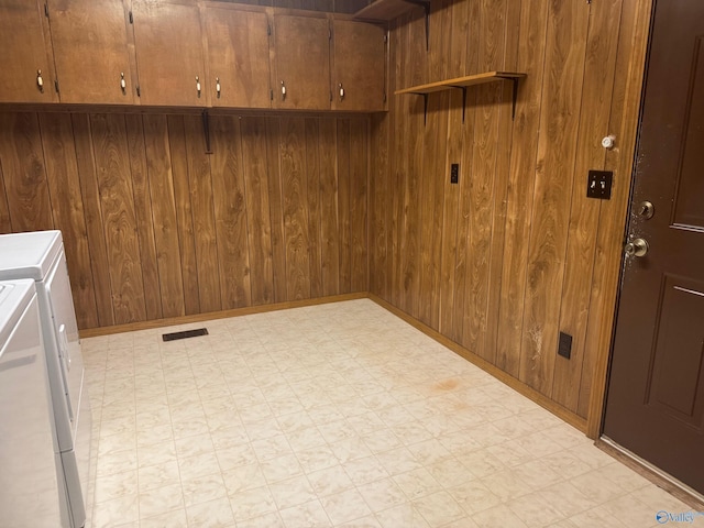 washroom featuring washer and clothes dryer, wood walls, and cabinets