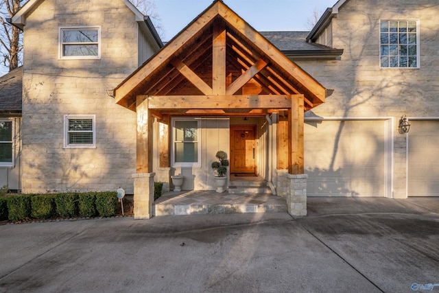 property entrance with concrete driveway, a garage, and a shingled roof