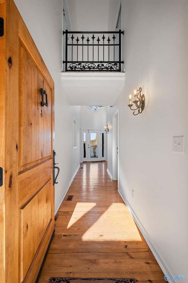 entryway featuring visible vents, baseboards, a high ceiling, and light wood finished floors