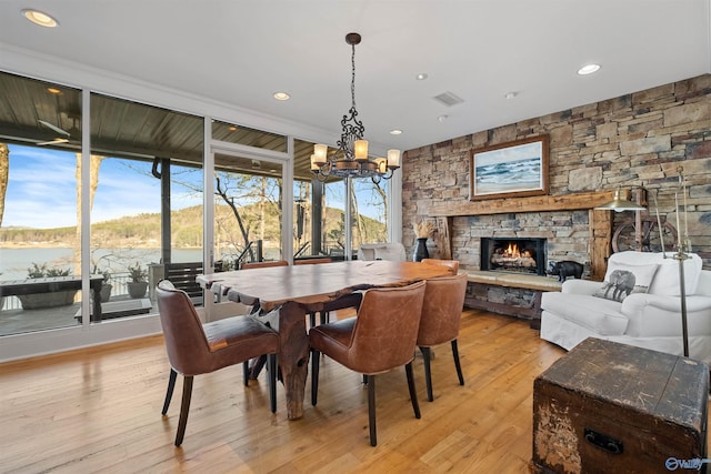 dining area featuring light wood-type flooring, visible vents, recessed lighting, a fireplace, and a chandelier