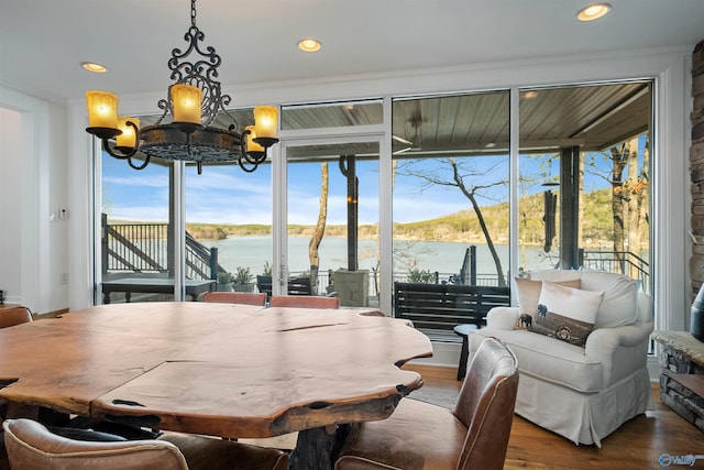 dining space with recessed lighting, wood finished floors, a water view, and a chandelier