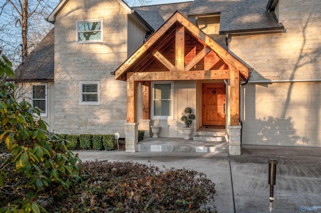 view of front of home featuring stone siding, driveway, roof with shingles, and an attached garage