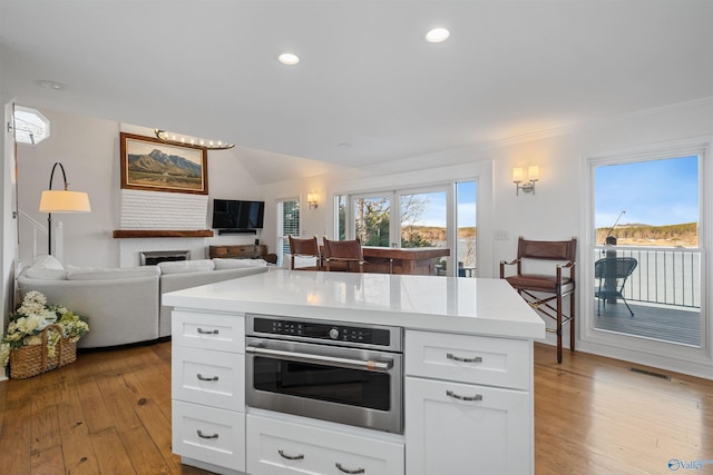 kitchen featuring stainless steel oven, visible vents, a healthy amount of sunlight, and light wood finished floors