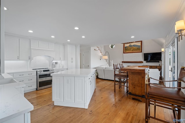 kitchen with open floor plan, a center island, white cabinets, light wood finished floors, and range with two ovens