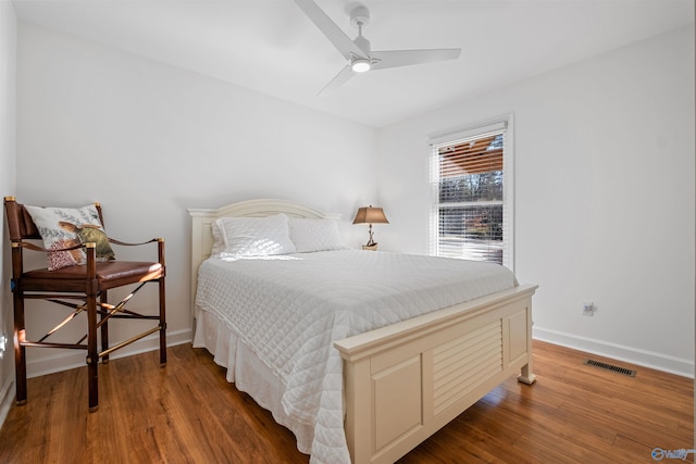 bedroom featuring visible vents, a ceiling fan, baseboards, and wood finished floors