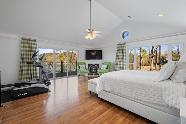 bedroom with wood finished floors, visible vents, a lit fireplace, vaulted ceiling, and access to outside