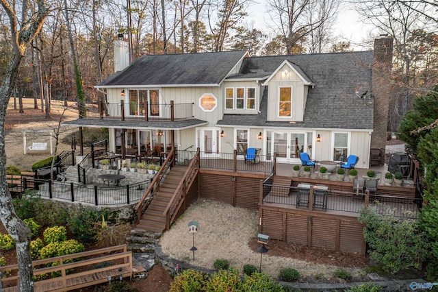 back of house featuring a chimney, a patio, french doors, roof with shingles, and stairs