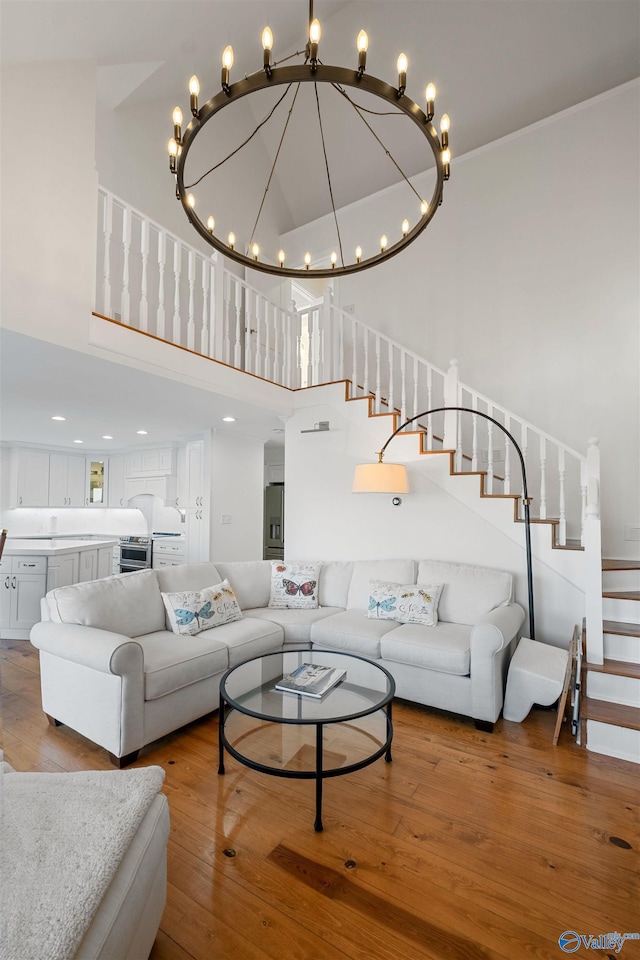 living room with wood-type flooring, a towering ceiling, and stairs