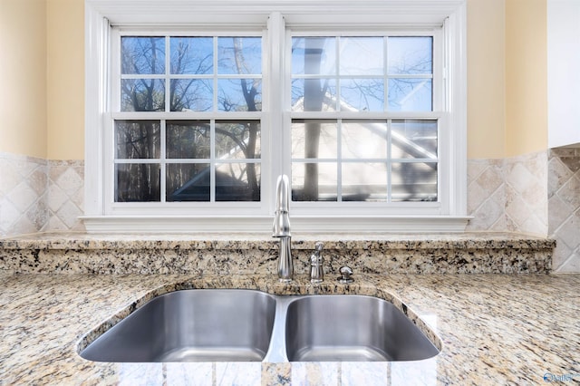 room details featuring light stone counters and a sink