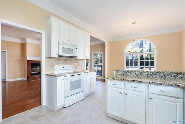 kitchen with white appliances, white cabinets, ornamental molding, an inviting chandelier, and backsplash