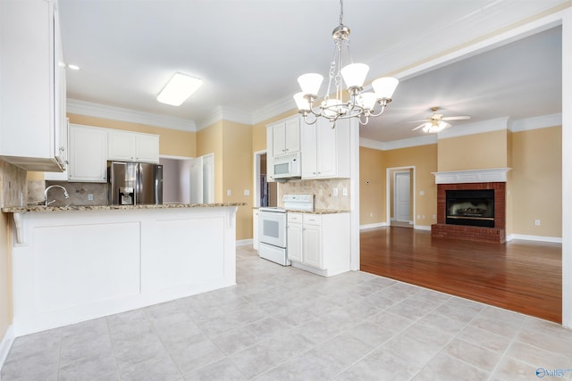 kitchen with light stone counters, white appliances, white cabinetry, and open floor plan