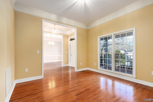 empty room with an inviting chandelier, baseboards, wood finished floors, and ornamental molding