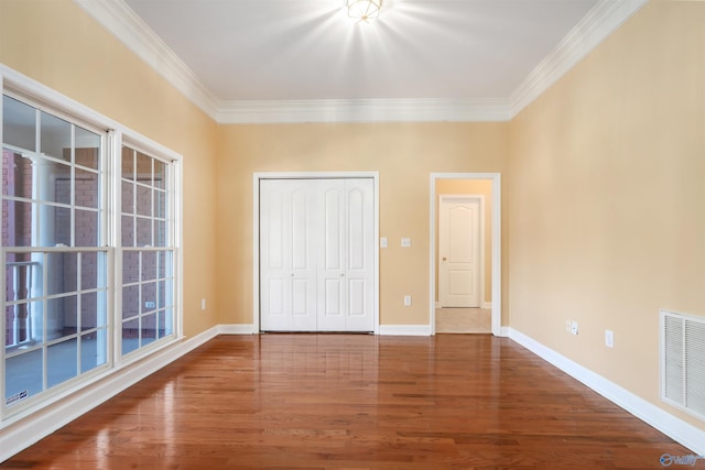 unfurnished bedroom featuring baseboards, crown molding, visible vents, and wood finished floors