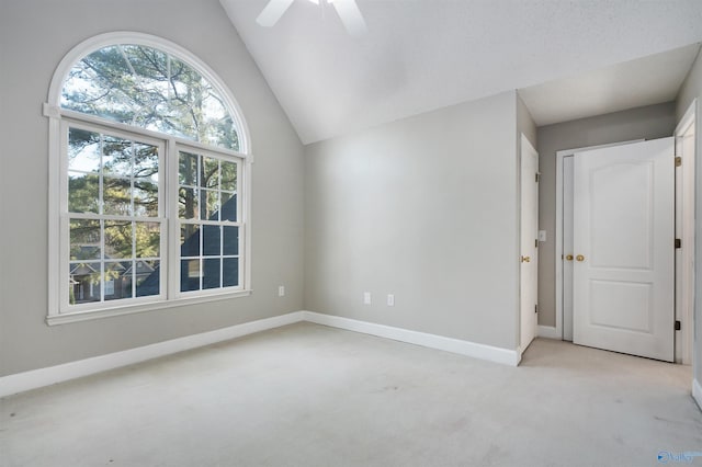 unfurnished room with light carpet, lofted ceiling, a ceiling fan, and baseboards