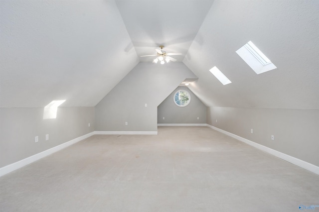 additional living space featuring light colored carpet, vaulted ceiling, baseboards, and ceiling fan