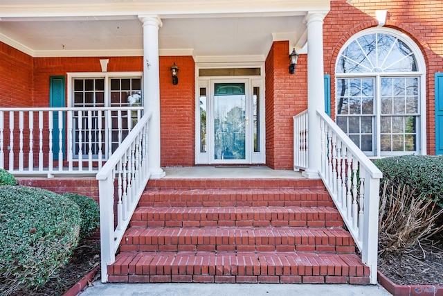 entrance to property featuring brick siding and a porch