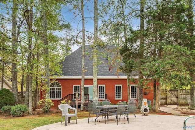 rear view of house featuring a patio area, brick siding, and fence