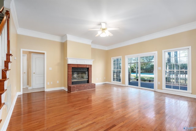 unfurnished living room with crown molding, a fireplace, light wood-style floors, a ceiling fan, and baseboards