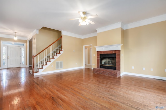 unfurnished living room featuring hardwood / wood-style flooring, visible vents, baseboards, ornamental molding, and stairway