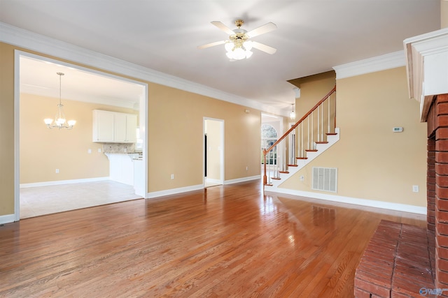 unfurnished living room featuring visible vents, light wood-style flooring, stairway, crown molding, and ceiling fan with notable chandelier