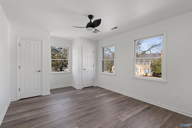 unfurnished bedroom with ceiling fan, dark hardwood / wood-style flooring, and multiple windows