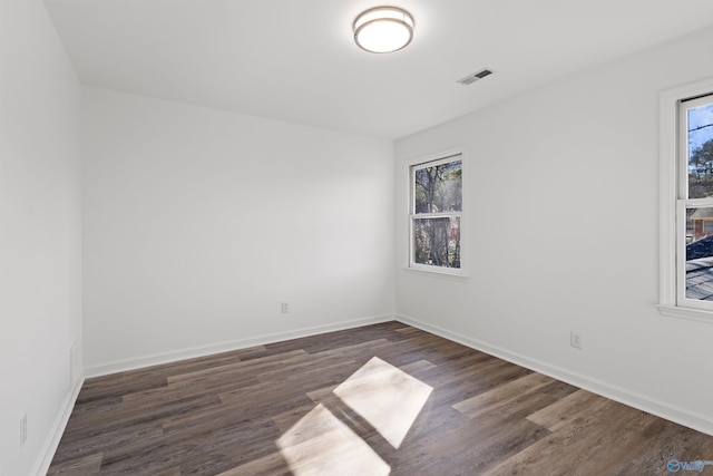 spare room featuring plenty of natural light and dark hardwood / wood-style flooring