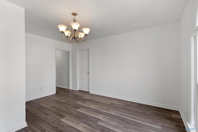 empty room featuring dark hardwood / wood-style floors and a notable chandelier