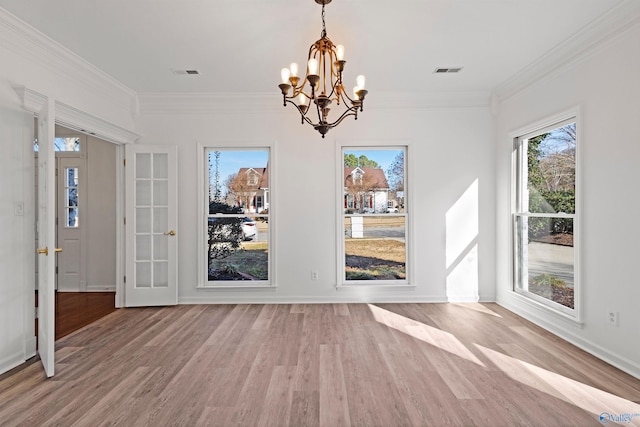 unfurnished dining area with hardwood / wood-style floors, crown molding, and a notable chandelier