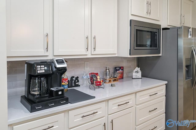 kitchen with tasteful backsplash, white cabinets, and appliances with stainless steel finishes