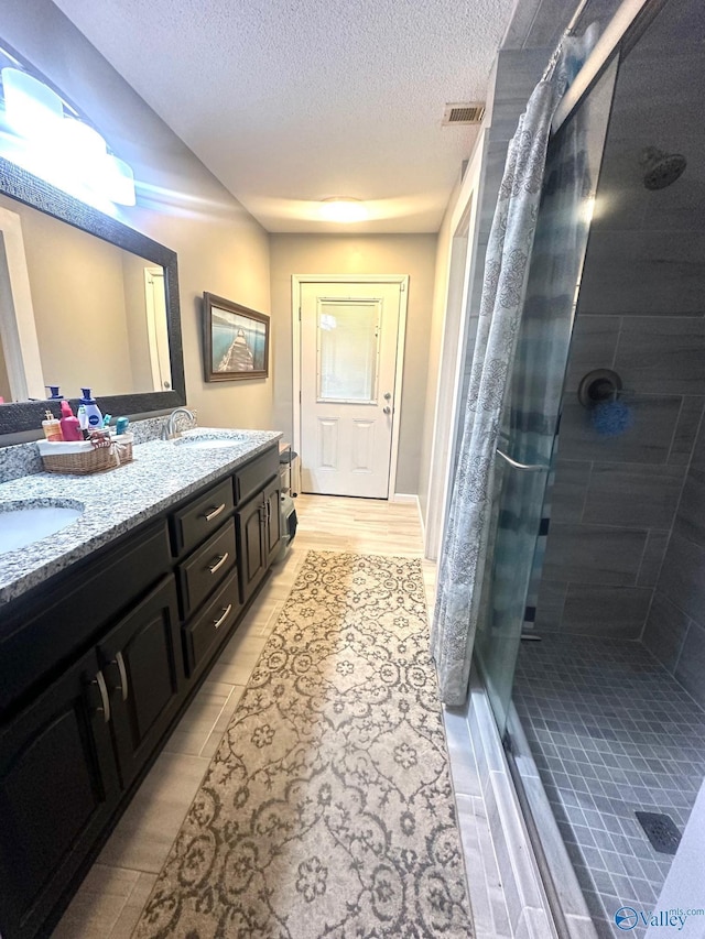 173 N Seneca Dr, Trinity, AL 35673 - bathroom featuring a stall shower, double vanity, and a textured ceiling