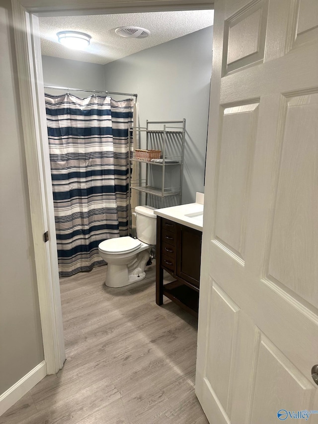 173 N Seneca Dr, Trinity, AL 35673 - full bathroom with toilet, vanity, wood finished floors, a textured ceiling, and a shower with curtain