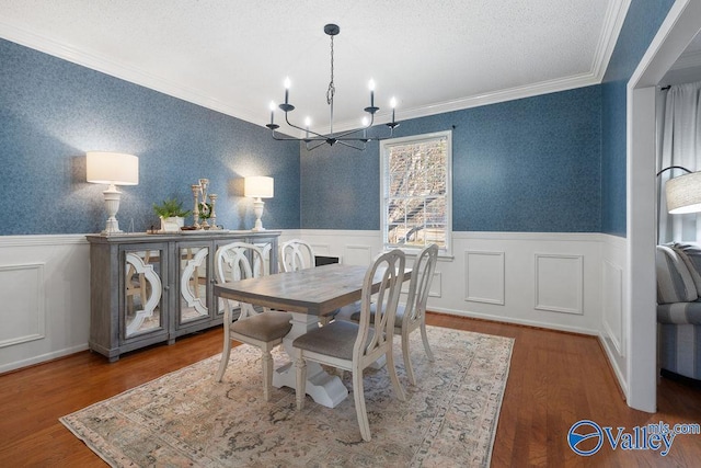 dining room with a textured ceiling, a chandelier, crown molding, and hardwood / wood-style floors