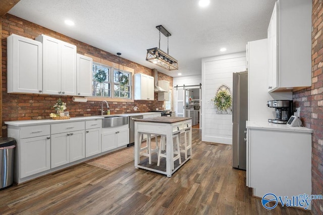 kitchen featuring decorative light fixtures, a barn door, sink, white cabinets, and dark hardwood / wood-style flooring