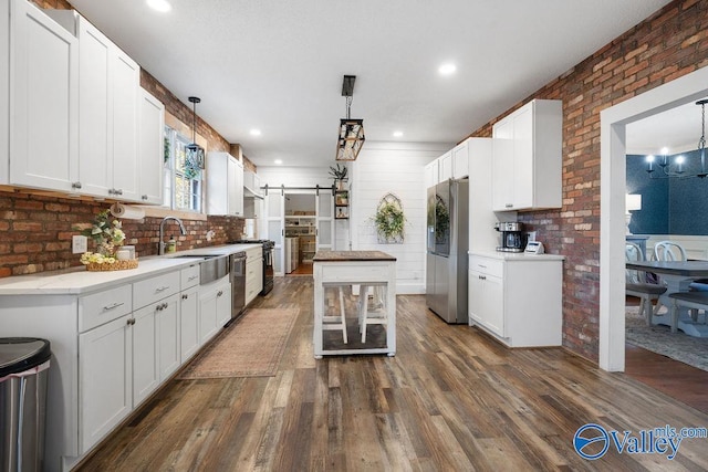 kitchen with dark hardwood / wood-style floors, stainless steel appliances, white cabinets, and hanging light fixtures