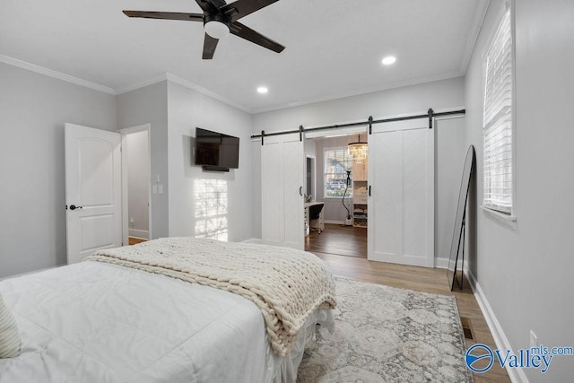 bedroom with ceiling fan, hardwood / wood-style floors, ornamental molding, and a barn door