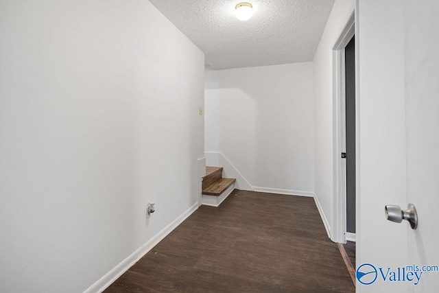 corridor with dark hardwood / wood-style flooring and a textured ceiling