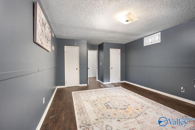 unfurnished bedroom with a textured ceiling and dark hardwood / wood-style flooring